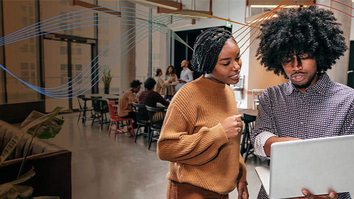 Two people standing in an office looking at a laptop