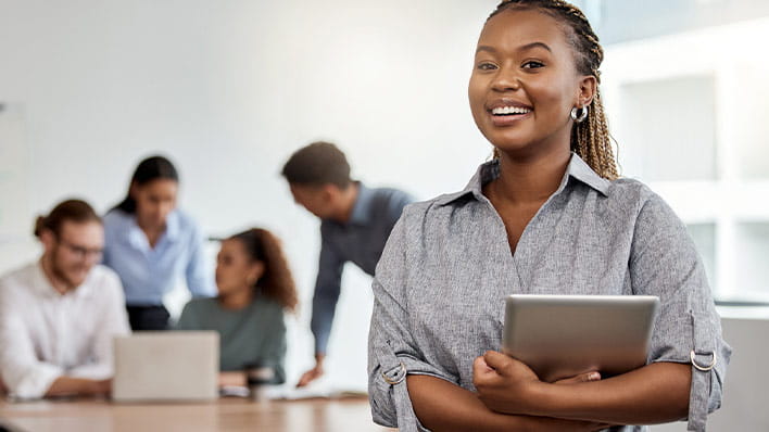Smiling woman in foreground with group meeting in background