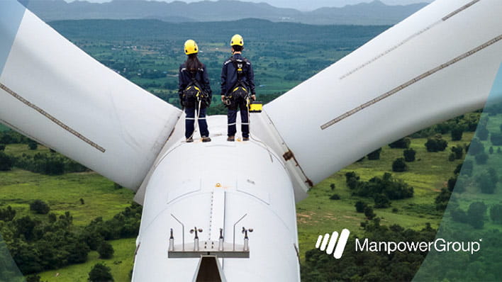 Two people standing on a wind turbine