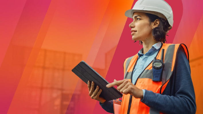 Person wearing a hard hat holding a tablet.