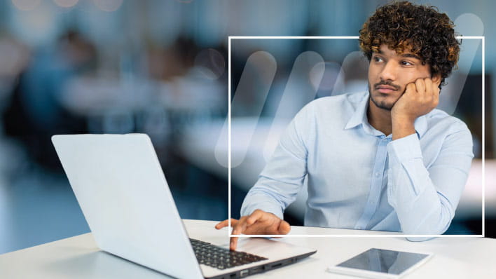 Person sitting in front of a laptop staring off into the distance.